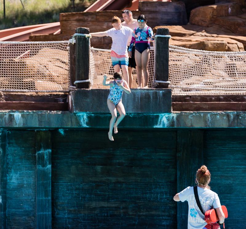 Alex Parris acting as a lifeguard while attendees of flok Family Camp West jump into a pool.